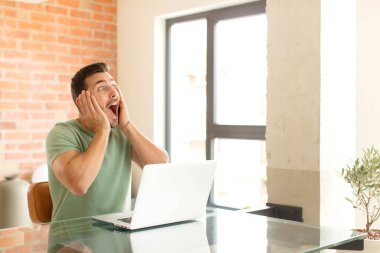 Yakışıklı adam mutlu, heyecanlı ve şaşırmış hissediyor, iki eli yüzü yana bakıyor.