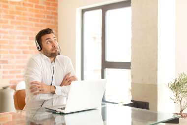 Yakışıklı pazarlamacı omuz silkiyor, kafası karışık ve emin değil, kolları bağlı ve şaşkın görünüyor.
