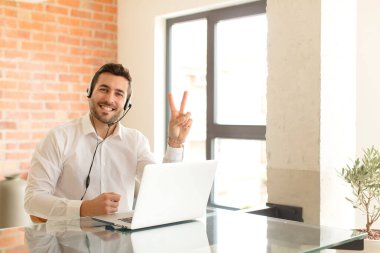 Yakışıklı pazarlamacı gülümsüyor ve mutlu görünüyor, kaygısız ve pozitif, zafer ya da barışı simgeliyor.