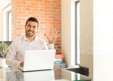 Yakışıklı iş adamı gülümsüyor ve dost canlısı görünüyor, 5 ya da 5 numarayı gösteriyor, elleri önde, geriye doğru sayıyor.
