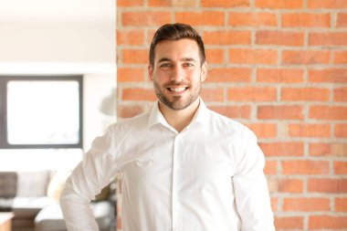 Yakışıklı işadamı mutlu bir şekilde gülümsüyor. Kendine güvenen, olumlu, gururlu ve arkadaş canlısı bir tavırla.