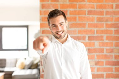 Yakışıklı iş adamı kameraya bakıyor. Tatmin olmuş, kendine güvenen, dost canlısı bir gülümsemeyle seni seçiyor.
