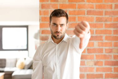Yakışıklı iş adamı kızgın, sinirli, hayal kırıklığına uğramış ya da hoşnutsuz, ciddi bir bakışla başparmağını kaldırıyor.