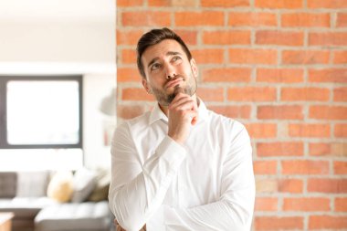 Yakışıklı iş adamı düşünüyor, kuşkulu ve şaşkın hissediyor, farklı seçenekleri var, hangi kararı vereceğini merak ediyor.