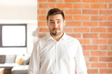 Yakışıklı işadamı şaşırmış ve kafası karışmış görünüyor. Sinirli bir hareketle dudağını ısırıyor. Sorunun cevabını bilmiyor.