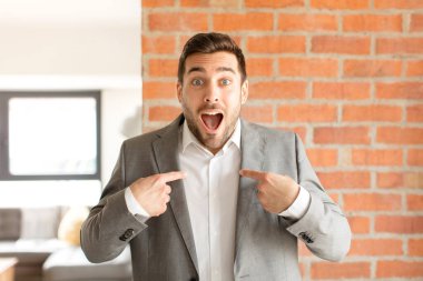 Yakışıklı iş adamı mutlu, şaşkın ve gururlu, heyecanlı, şaşkın bakışlarla kendini işaret ediyor.
