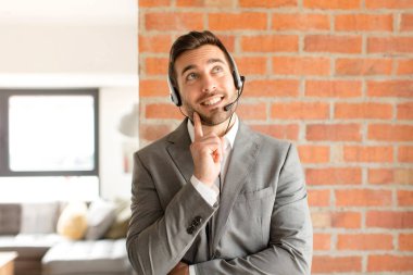 Yakışıklı pazarlamacı mutlu bir şekilde gülümsüyor ve hayal kuruyor ya da şüphe ediyor.