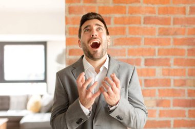 Yakışıklı iş adamı umutsuz ve hayal kırıklığına uğramış görünüyor, stresli, mutsuz ve sinirli, bağırıyor ve çığlık atıyor.