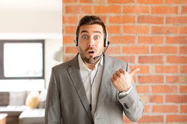 Yakışıklı pazarlamacı inançsızlıktan şaşkın şaşkın bakıyor, yan taraftaki objeyi işaret ediyor ve diyor ki: