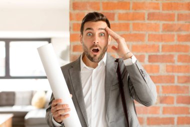 Yakışıklı mimar mutlu, şaşkın ve şaşırmış görünüyor, gülümsüyor ve inanılmaz ve inanılmaz iyi haberleri fark ediyor.