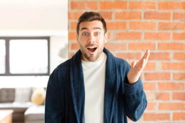 Yakışıklı adam kendini mutlu, şaşırmış ve neşeli hissediyor. Pozitif bir tavırla gülümsüyor. Bir çözüm ya da fikir buluyor.