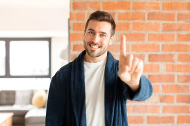 Yakışıklı adam gururla gülümsüyor ve gururla bir numaralı pozunu veriyor, kendini lider gibi hissediyor.