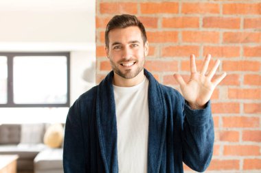 Yakışıklı adam gülümsüyor ve arkadaş canlısı görünüyor, 5 ya da 5 numarayı gösteriyor, eli önde, geri sayıyor.