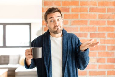 Yakışıklı adam şaşkın ve şaşkın, şüpheci, farklı seçenekleri tartıyor ya da komik bir ifadeyle seçiyor.