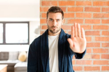 Yakışıklı adam ciddi, sert, hoşnutsuz ve kızgın görünüyor. Avuç içini açıp jesti durduruyor.