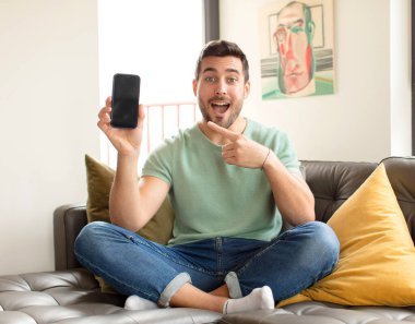 Yakışıklı adam heyecanlı ve şaşırmış görünüyor. Yana ve yukarı doğru uzayı gösteriyor.