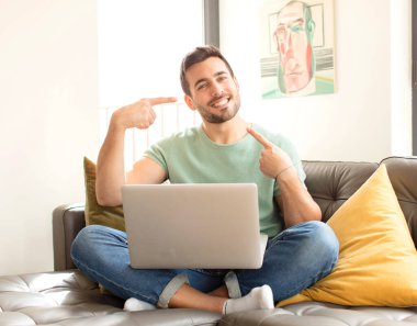 Yakışıklı adam kendinden emin bir şekilde gülümsüyor. Geniş bir gülümseme, pozitif, rahat, tatmin olmuş bir tavır sergiliyor.