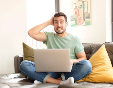 Yakışıklı bir adam stresli, endişeli, endişeli ya da korkmuş, elleri başının üstünde, hata yaptığında panikliyor.