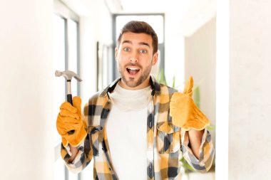 Becerikli, gururlu, tasasız, kendinden emin ve mutlu hisseden, başparmağıyla olumlu gülümseyen