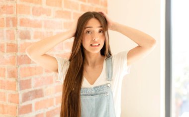 Güzel bir kadın kendini stresli, endişeli, endişeli ya da korkmuş hisseder. Elleri başının üstünde, hatayla panikler.