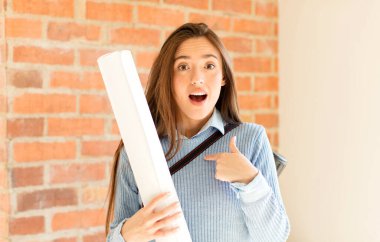 Güzel bir mimar ağzı açık, şaşkın ve şaşkın bir şekilde kendini işaret ediyor.