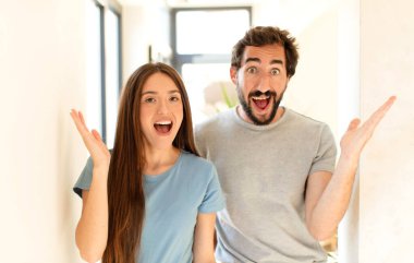 Genç çift mutlu, heyecanlı, şaşırmış ya da şaşırmış hissediyor, gülümsüyor ve hayrete düşüyor.