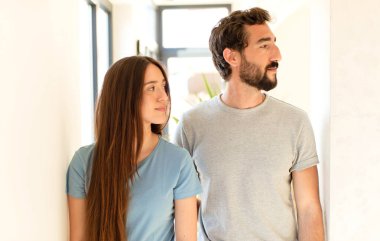 Profil görünümlü genç çift ilerideki boşluğu kopyalamak istiyor, düşünüyor, hayal ediyor ya da hayal kuruyor.