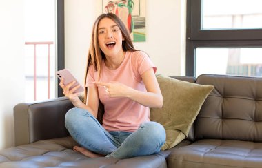 Güzel bir kadın heyecanlı ve şaşırmış görünüyor. Yana ve yukarı doğru uzayı gösteriyor.