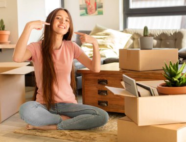 Güzel bir kadın, kendine güvenerek gülümseyerek kendi geniş gülümsemesini, pozitif, rahat, tatmin olmuş tavrını gösterir.