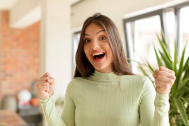 Güzel bir kadın mutlu, şaşırmış ve gururlu, bağırıyor ve başarıyı büyük bir gülümsemeyle kutluyor.