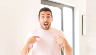 Yakışıklı adam mutlu, şaşkın ve gururlu, heyecanlı, şaşkın bakışlarla kendini işaret ediyor.