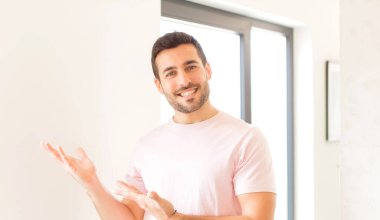 Yakışıklı adam gururla ve güvenle gülümsüyor, mutlu ve tatmin olmuş hissediyor ve fotokopi alanında bir konsept gösteriyor.