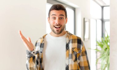 Yakışıklı adam kendini mutlu, şaşırmış ve neşeli hissediyor. Pozitif bir tavırla gülümsüyor. Bir çözüm ya da fikir buluyor.