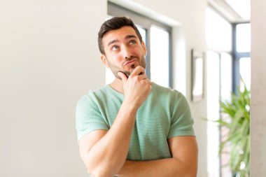 Yakışıklı düşünen, kuşkulu ve kafası karışık, farklı seçenekleri olan, hangi kararı vereceğini merak eden bir adam.