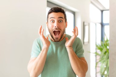 Yakışıklı bir adam beklenmedik bir sürprizden dolayı şaşkın ve heyecanlı, güler yüzlü, şaşkın ve mutlu hissediyor.
