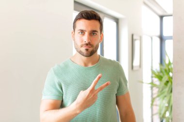 Yakışıklı adam kendini mutlu, pozitif ve başarılı hissediyor. Göğsünde el yapımı V şekli var. Zafer ya da barış gösteriyor.