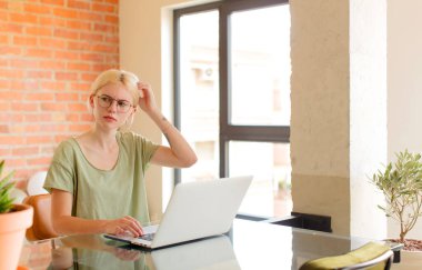 Güzel öğrenci şaşkın ve kafası karışmış hissediyor, kafasını kaşıyor ve yan tarafa bakıyor.