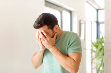 Yakışıklı adam, üzgün, hayal kırıklığına uğramış bir bakışla gözlerini kapatıyor, ağlıyor, yan gözle bakıyor.