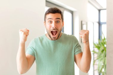 Yakışıklı adam mutlu, pozitif ve başarılı hissediyor, zaferi, başarıları veya iyi şansı kutluyor.