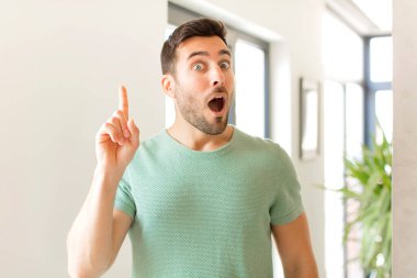 Yakışıklı bir adam bir fikri fark ettikten sonra mutlu ve heyecanlı bir dahi gibi hissediyor, neşeli bir şekilde parmağını kaldırıyor, eureka!