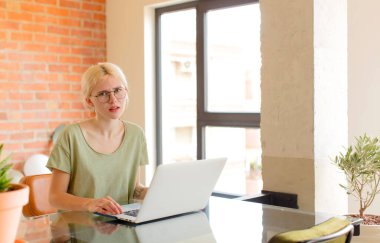 pretty student feeling puzzled and confused, with a dumb, stunned expression looking at something unexpected