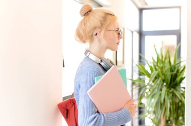 Profil görünümündeki güzel öğrenci boşluğu kopyalamaya çalışıyor, düşünüyor, hayal ediyor ya da hayal kuruyor.
