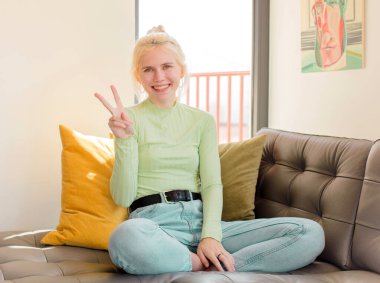 Güzel bir kadın gülümsüyor ve arkadaş canlısı görünüyor. İki ya da iki numarayı gösteriyor. Elleri önde, geri sayıyor.