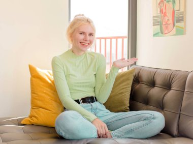 Güzel bir kadın neşeyle gülümsüyor, mutlu hissediyor ve bir konsepti fotokopi uzayında el ele vererek gösteriyor.