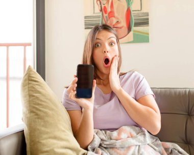 Güzel kadın şok olmuş ve korkmuş hissediyor, ağzı açık ve elleri yanaklarında korkmuş görünüyor.