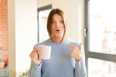 Şok olmuş ve ağzı açık, kendini işaret eden güzel bir kadın.