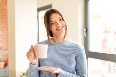 Güzel bir kadın neşeyle gülümsüyor, mutlu hissediyor ve bir konsepti fotokopi uzayında el ele vererek gösteriyor.