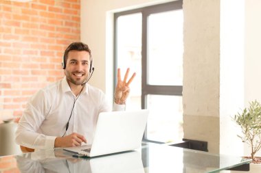 Yakışıklı pazarlamacı gülümsüyor ve arkadaş canlısı görünüyor. Üç ya da üç numarayı gösteriyor. Elleri önde, geriye doğru sayıyor.