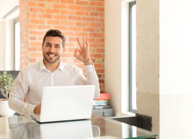 Yakışıklı iş adamı kendini mutlu, rahat ve tatmin olmuş hisseder. Onayını iyi bir hareketle gösterir.