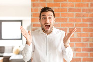 Yakışıklı iş adamı kendini mutlu, heyecanlı, şaşırmış ya da şaşırmış hisseder. İnanılmaz bir şeye gülümser ve şaşırır.